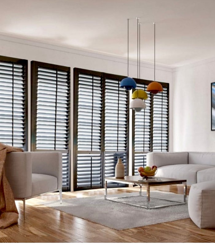 Norman shutters in a dark stained wood finish across a living room window wall