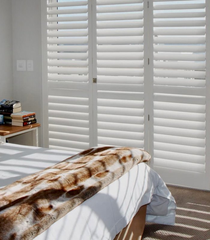 Bedroom wall of Norman shutters with louvers tilted to filter light