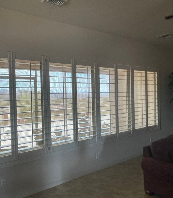 Whole-home install: a full wall of Norman shutters across a mountain-view window bank