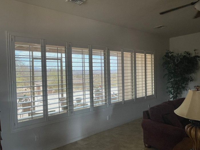 A full wall of Norman Woodlore shutters across a mountain-view window bank, the kind of span we fit in Paradise Valley, AZ