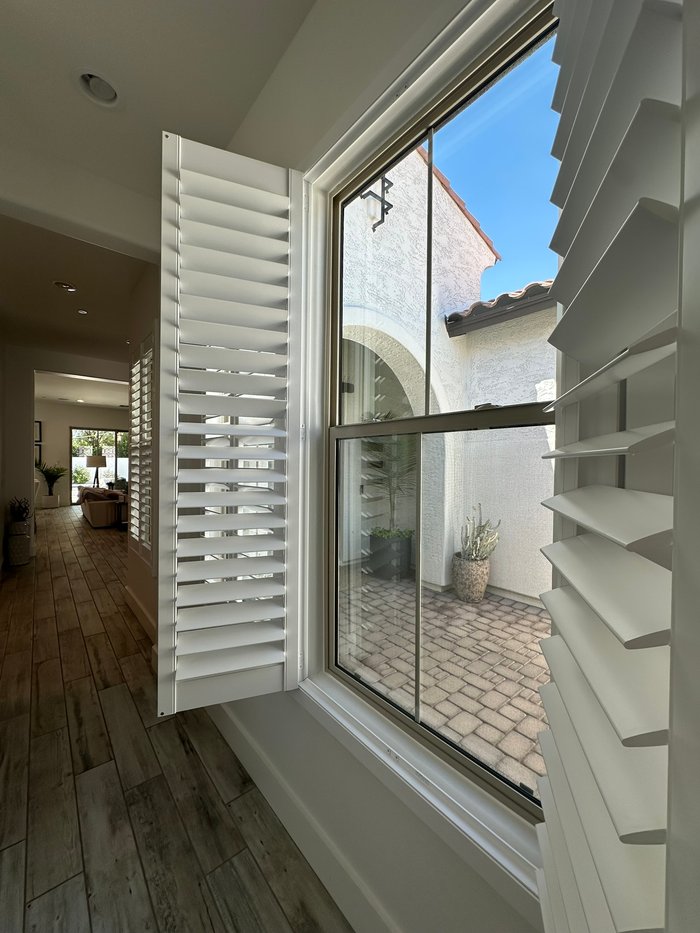 Large picture window with a shutter panel open to a paved courtyard, UV control for Paradise Valley, AZ interiors
