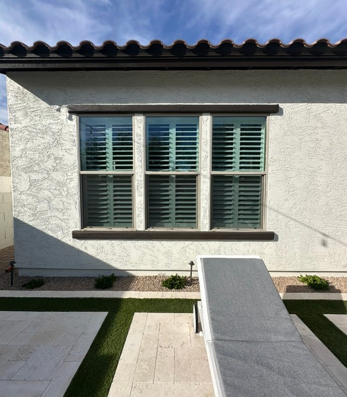Stucco exterior showing plantation shutters behind a three-panel window