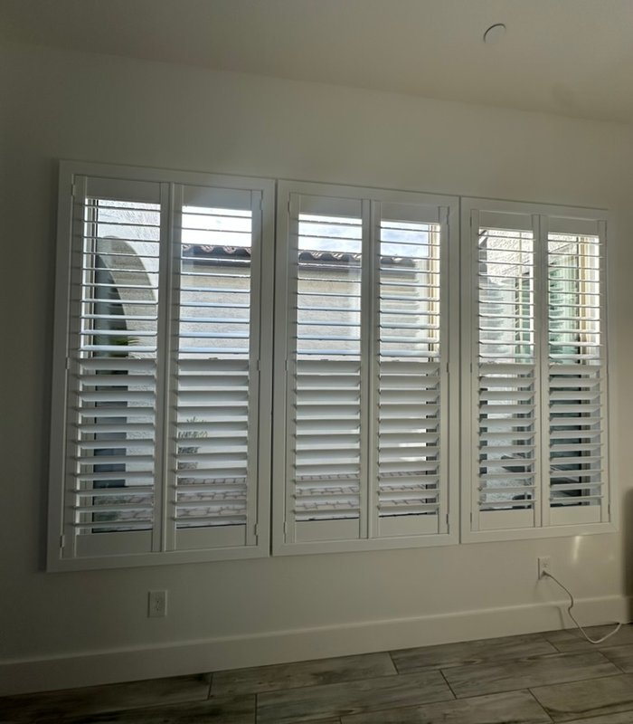 Wide multi-panel plantation shutter spanning an entire living room wall