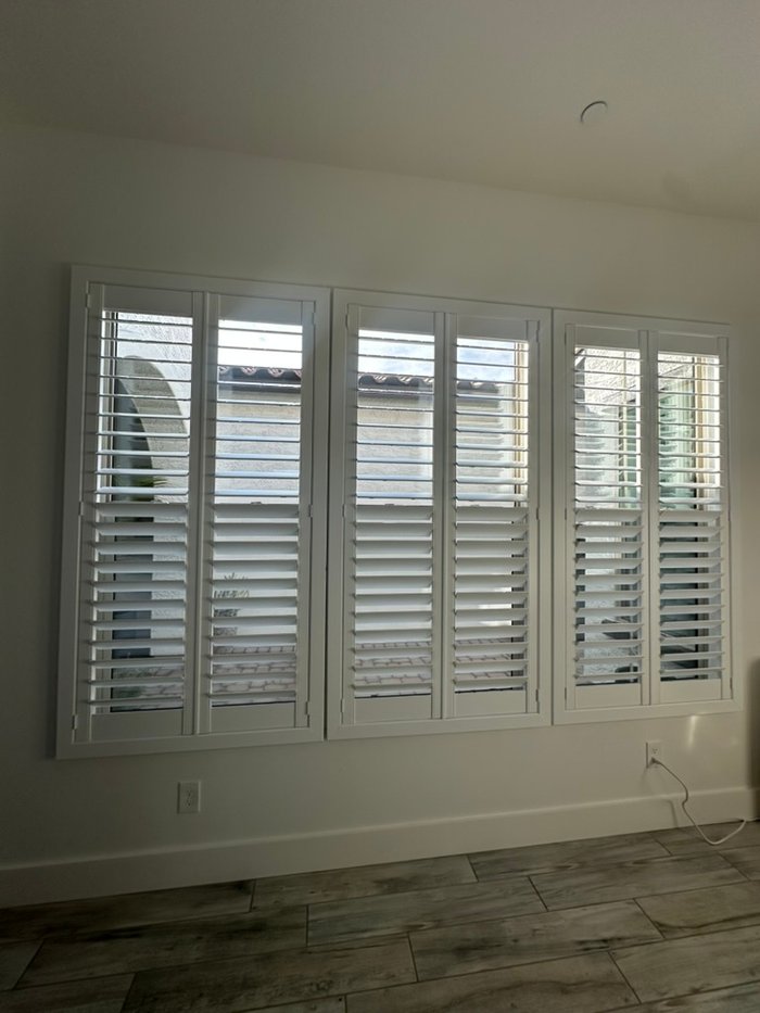 Wide multi-panel plantation shutter spanning a living room wall, the scale of glass common in Carefree, AZ