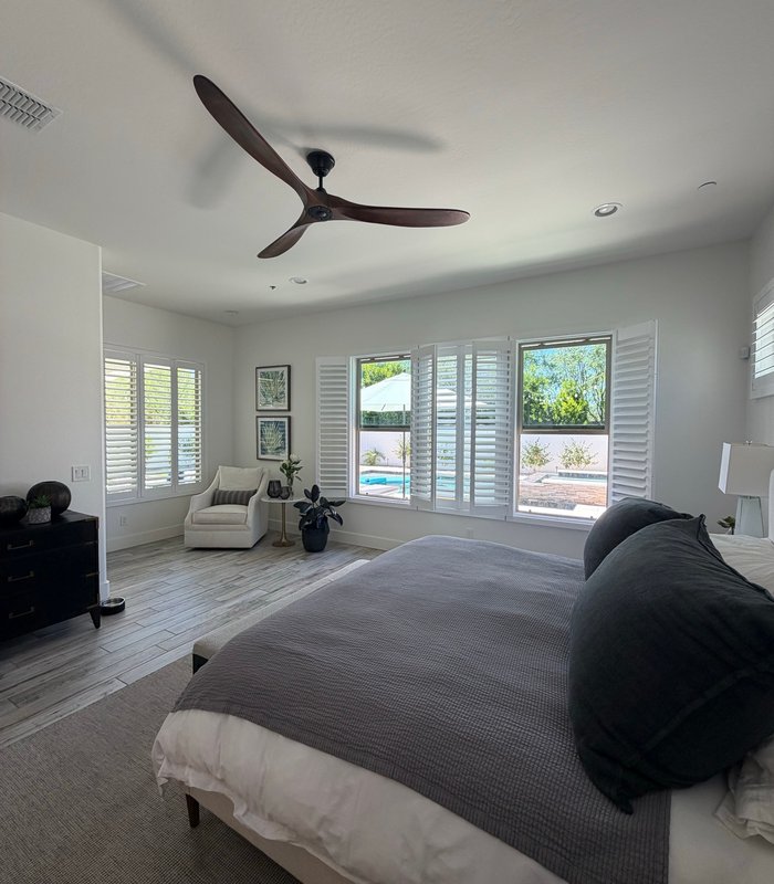 Master bedroom with white plantation shutters across a window wall looking out to the pool
