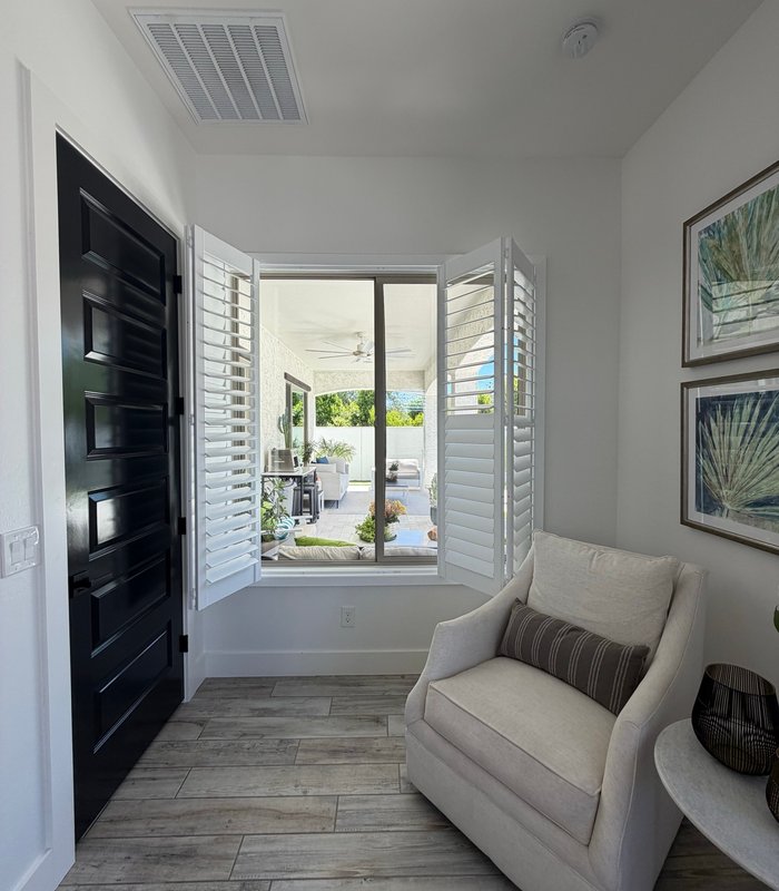 Entry sitting area with Norman shutters folded fully open to a shaded patio and courtyard