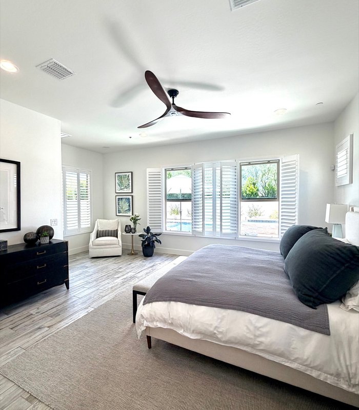 Master bedroom with Norman plantation shutters on a corner window and pool view