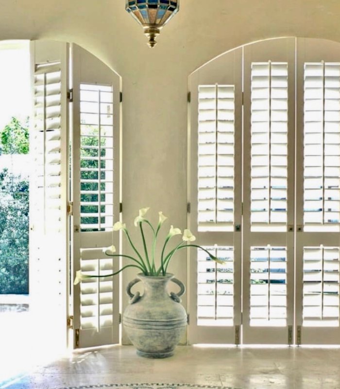 Arched Norman shutter doors opened onto a garden entry