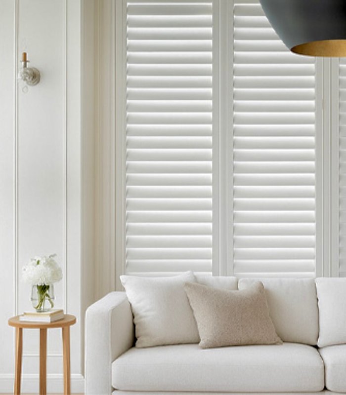 Norman shutters closed behind a living room sofa, showing full light block