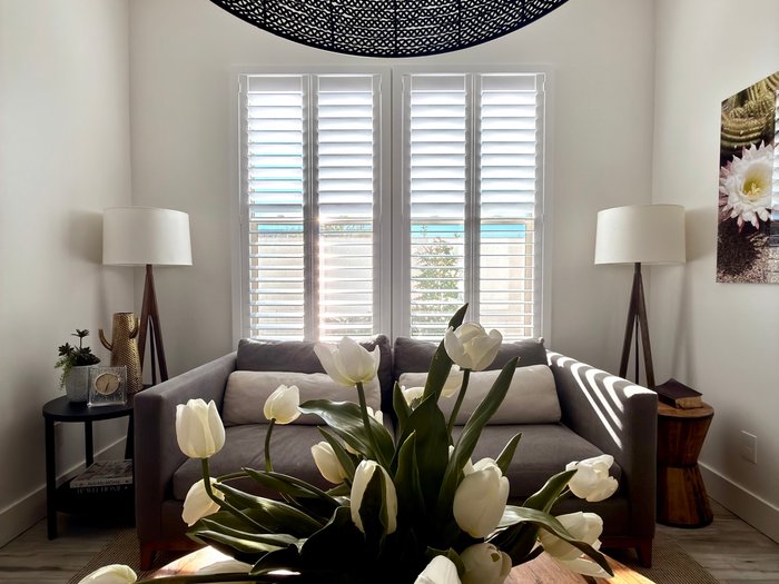 White Norman shutters against light trim in a sunlit sitting room, the kind of neutral finish most Scottsdale, AZ HOAs approve