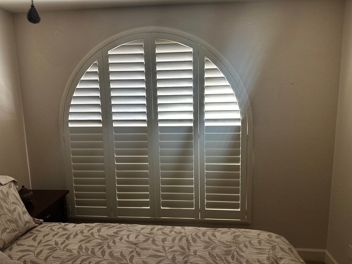 Arched window fitted with a custom half-round Norman shutter, the specialty shape work we do in Carefree, AZ