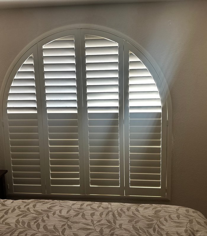 Arched bedroom window fitted with a custom half-round plantation shutter