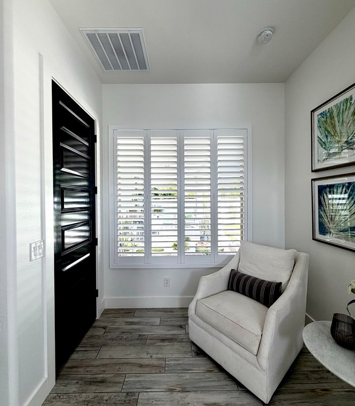 Entry sitting area beside a dark wood front door, Norman shutters closed across the window