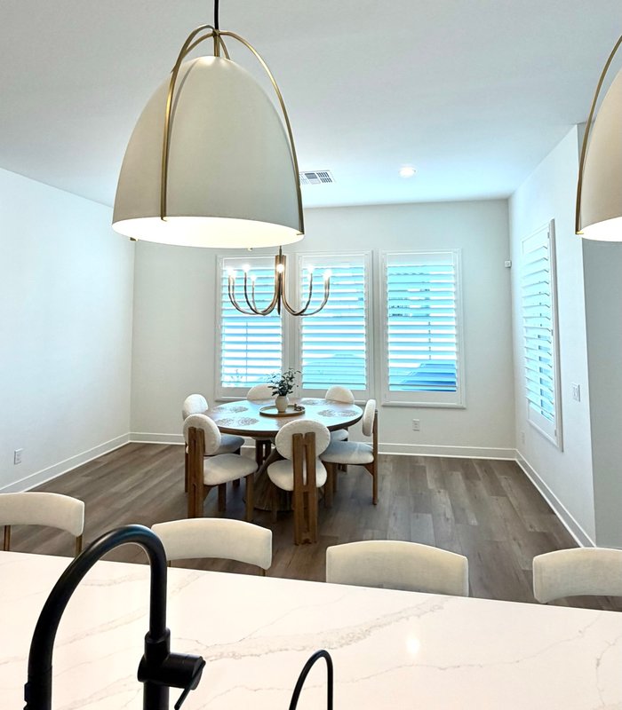 View from the kitchen island to a dining nook framed by white plantation shutters