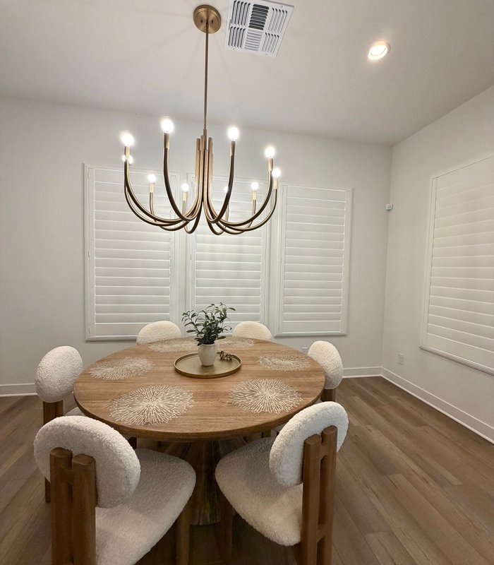 Dining room under a brass chandelier with Norman shutters closed across the window bank