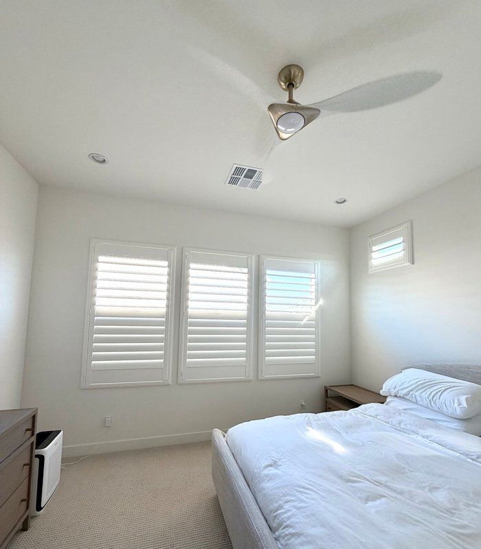Bedroom with a three-panel Norman shutter bank and a separate shuttered transom window