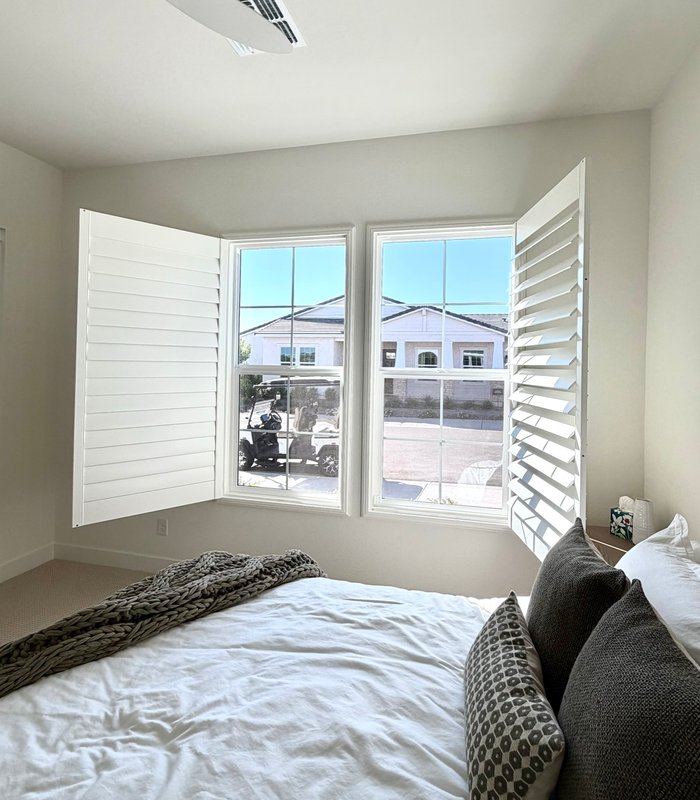 Bedroom corner windows with Norman shutter panels swung wide to the morning light