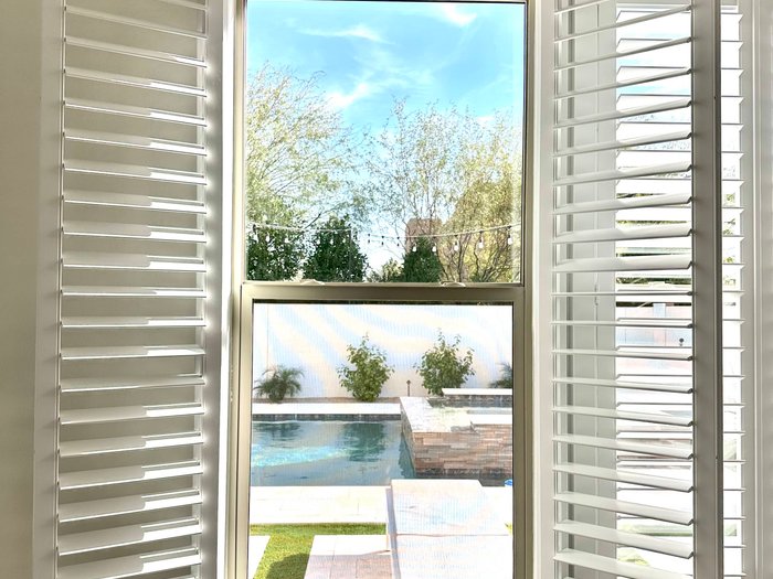 Full-height Norman shutter panels folded back off a large glass opening in a Mesa, AZ home