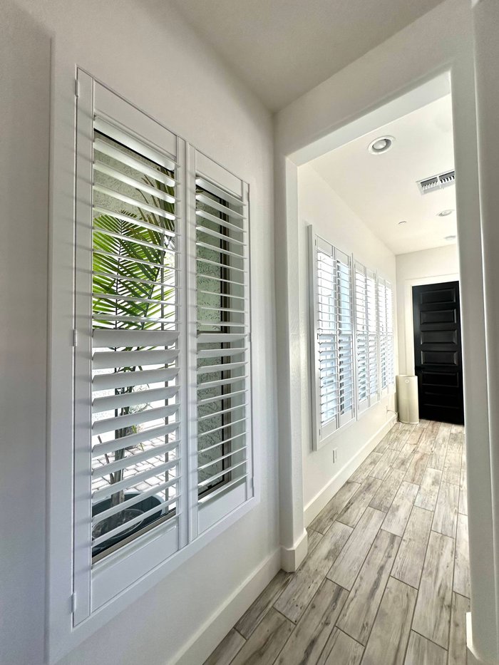 Hallway lined with floor-to-ceiling plantation shutters, a whole-home install of the type we do in Paradise Valley, AZ