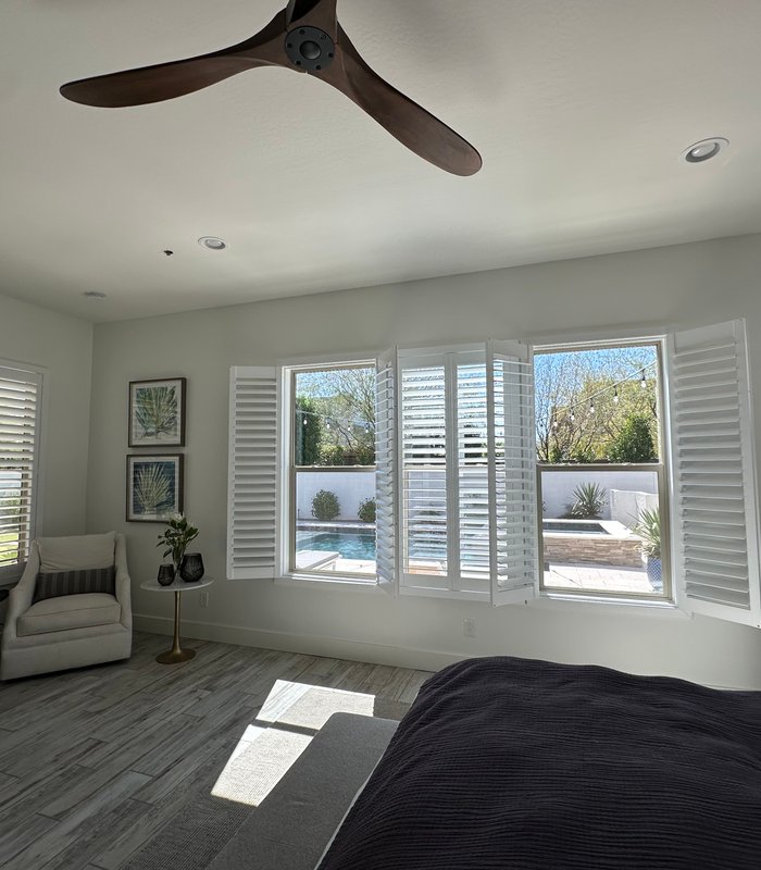 Bedroom bay window with Norman shutter panels swung open to a pool and courtyard view